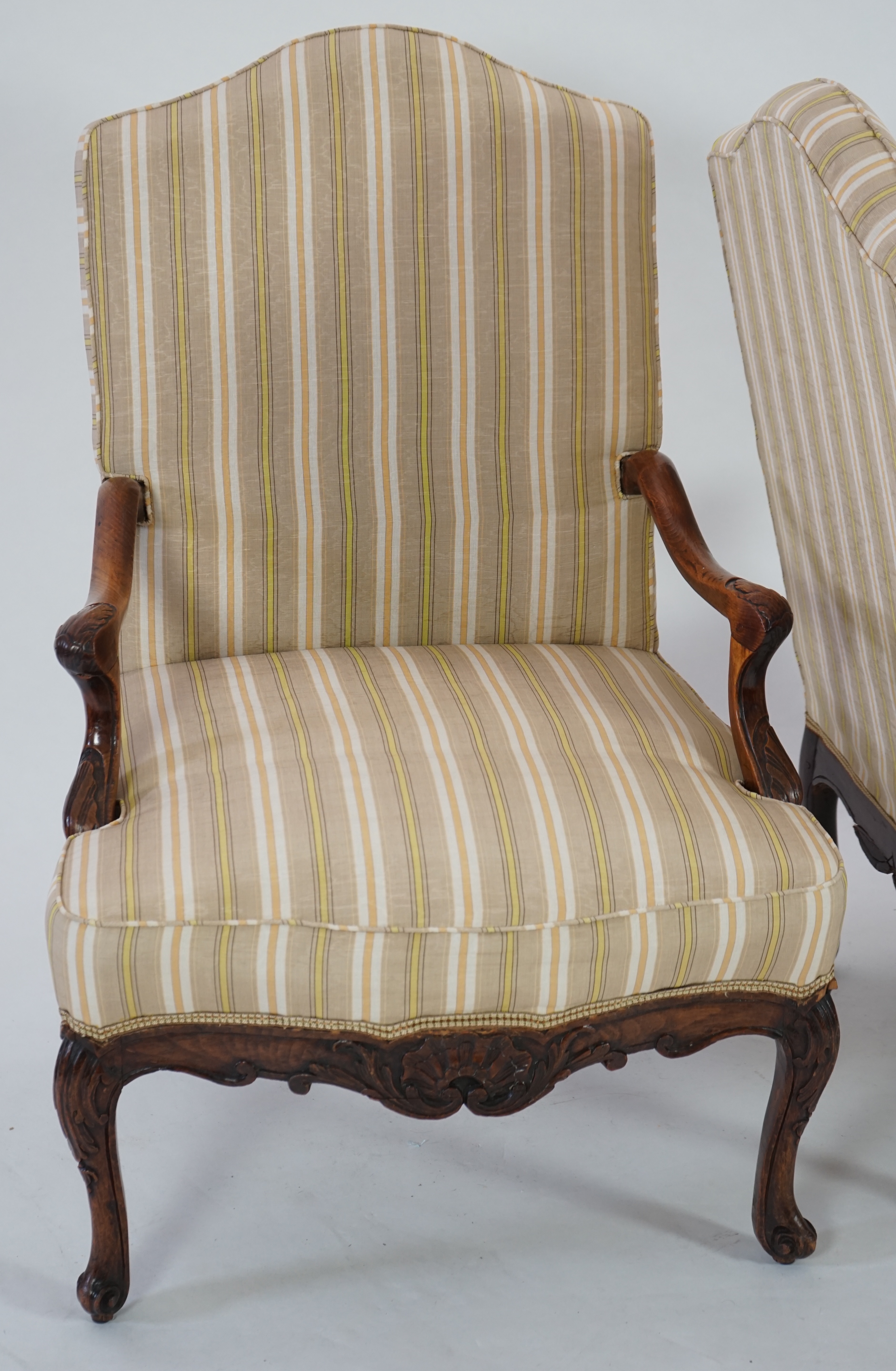 A pair of Louis XVI walnut fauteuils with upholstered backs and seats and foliate carved arms and underframes, on cabriole legs, width 67cm, depth 76cm, height 104cm. Condition - fair